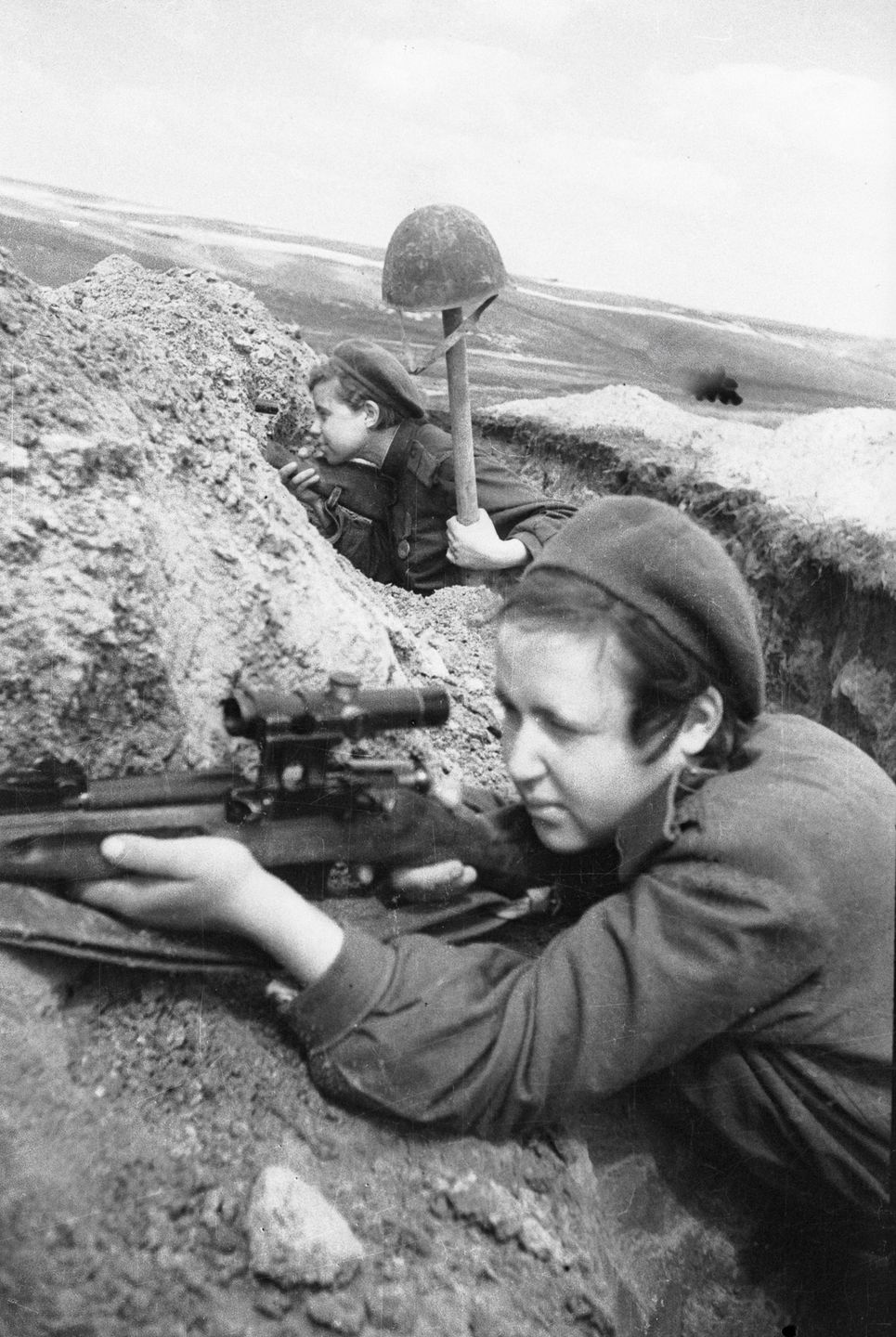 Photo of two female Soviet snipers in a trench, actively scanning for targets